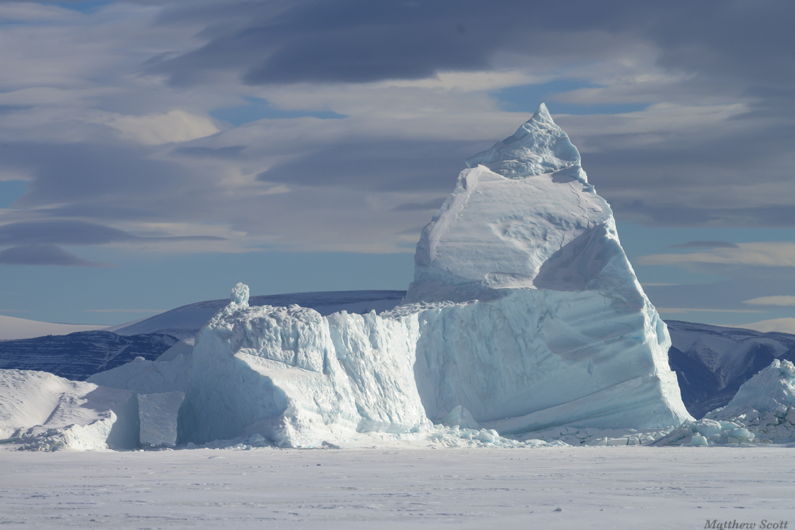 Iceberg embedded in frozen ocean
